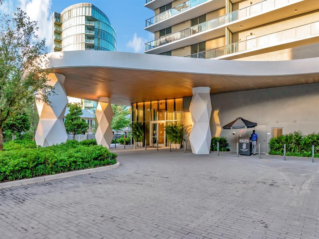 A modern building entrance features a curved canopy supported by geometric white pillars and valet — 3101 W BAYSHORE BOULEVARD UNIT 2304, TAMPA, FL
