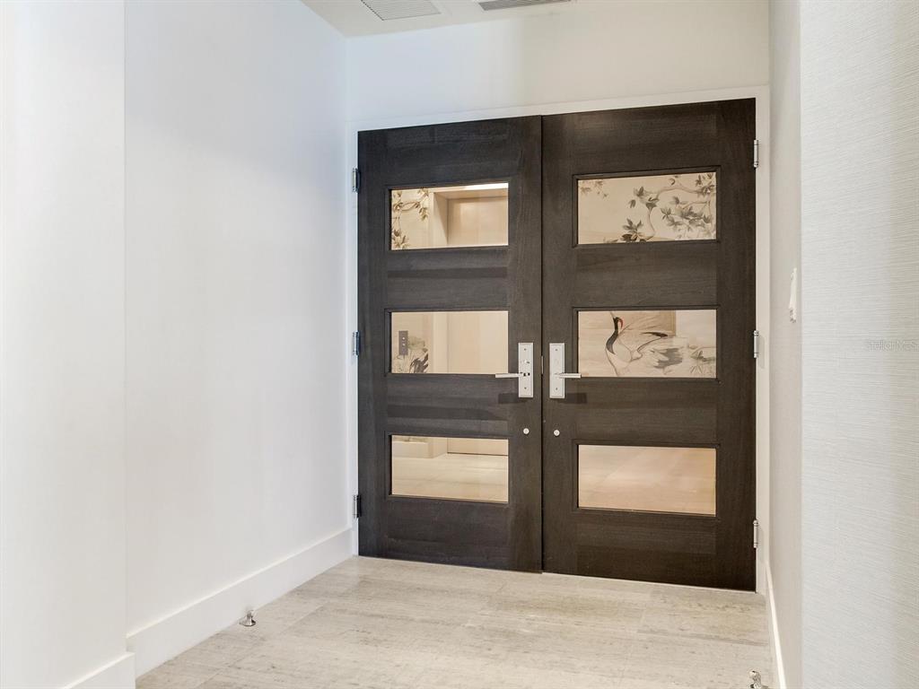 A modern entryway features double dark wood doors with decorative glass panels and light flooring — 3101 W BAYSHORE BOULEVARD UNIT 2304, TAMPA, FL