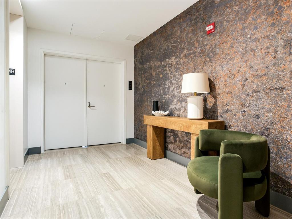 A modern hallway features a textured accent wall, a wooden console table, and a green chair — 3101 W BAYSHORE BOULEVARD UNIT 402, TAMPA, FL