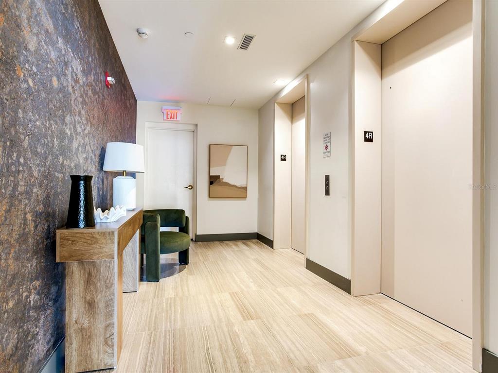 A modern hallway features a textured accent wall, a console table, and two elevator doors — 3101 W BAYSHORE BOULEVARD UNIT 402, TAMPA, FL