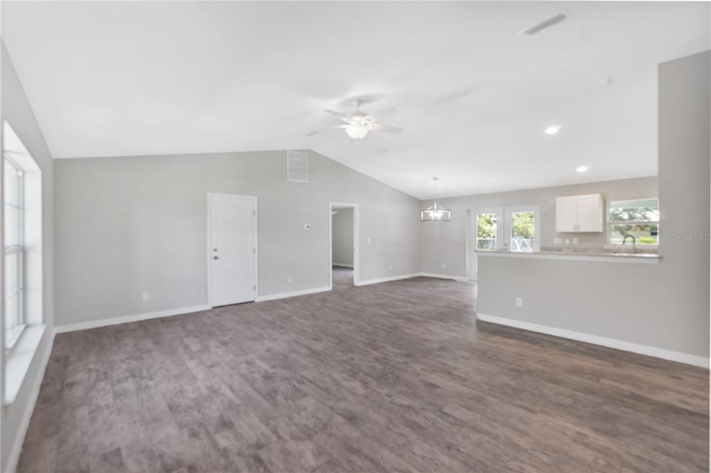 An open-concept living area with vaulted ceilings, gray walls, and wood-look flooring — 12107 BROOKSIDE AVENUE, PORT CHARLOTTE, FL