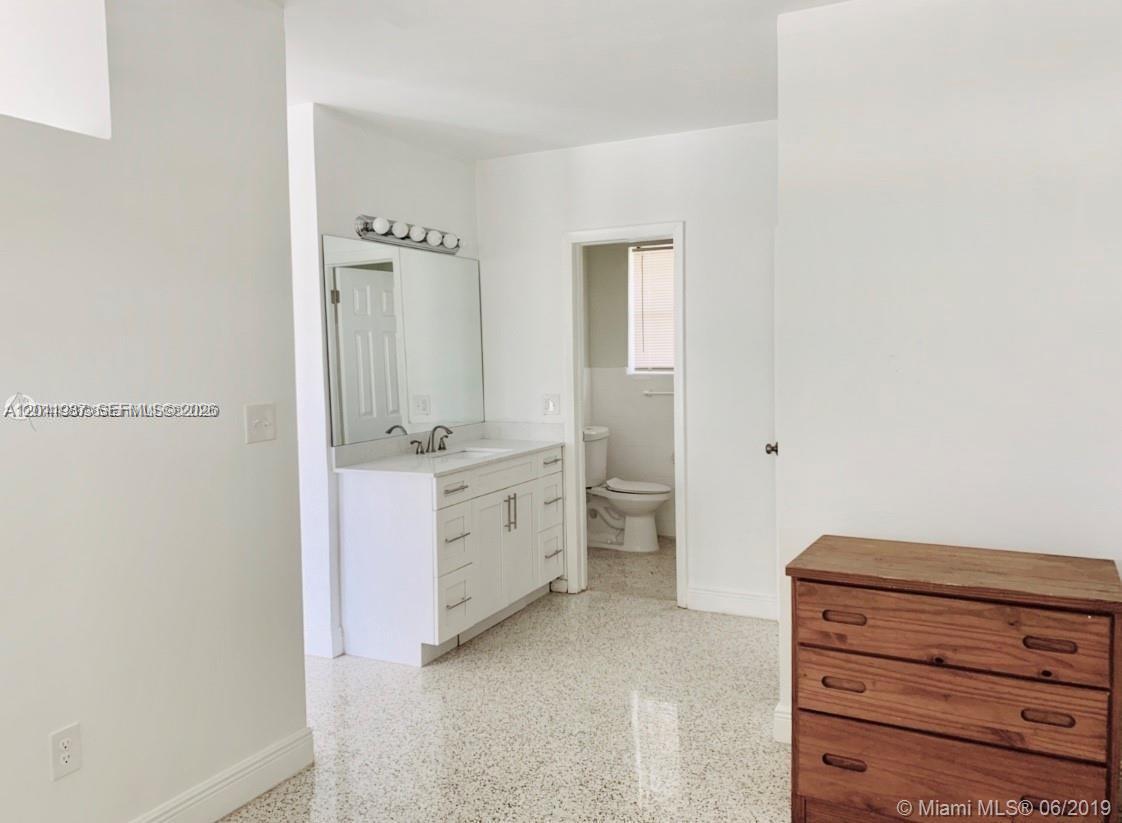 A bathroom vanity with a mirror sits in a room with terrazzo flooring — 7731 NW 2nd Ave # 6, Miami FL 33150, MIAMI, FL