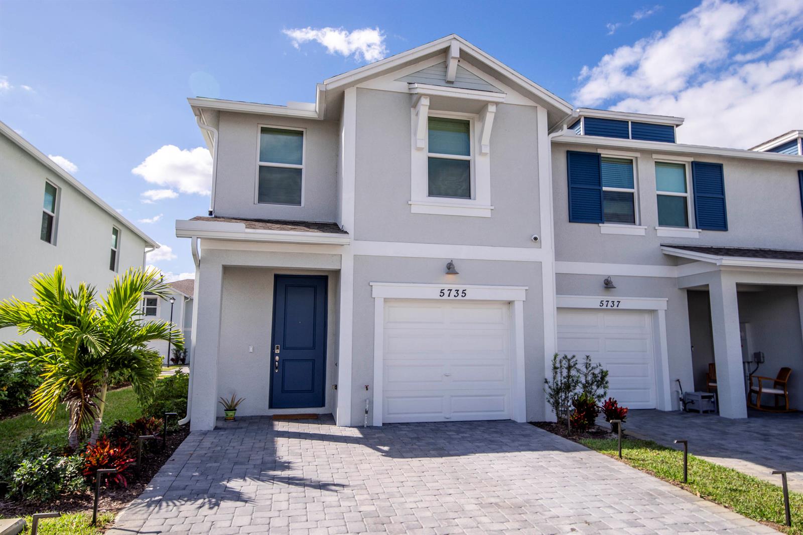 A two-story gray townhouse features a blue front door, white garage, and paved driveway — 5735 SE Edgewater Circle, Stuart FL 34997, STUART, FL