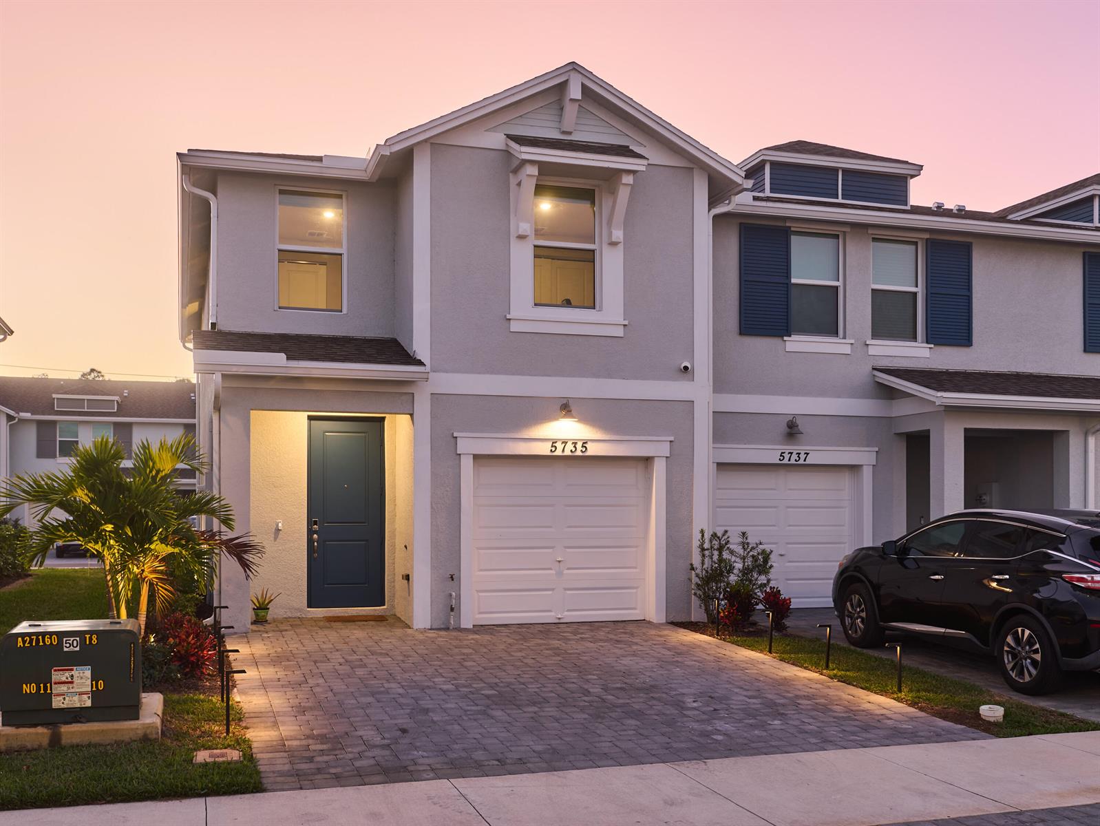 A two-story townhouse exterior features a gray stucco facade, a blue front door, and a driveway — 5735 SE Edgewater Circle, Stuart FL 34997, STUART, FL