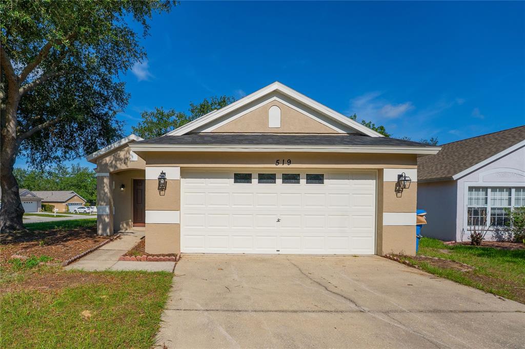 A single-story house with a beige stucco exterior, a two-car garage, and a concrete driveway — 519 SUMMER SAILS DRIVE, VALRICO, FL