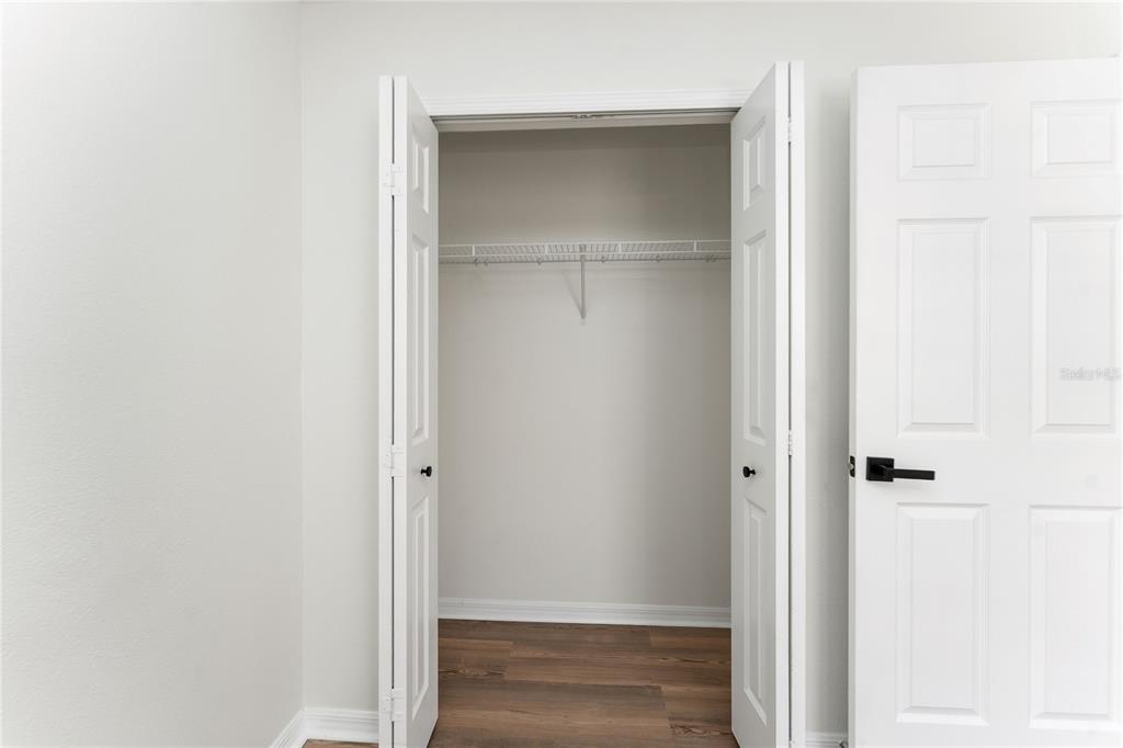 A closet with white bifold doors and wire shelving sits next to a closed door — 519 SUMMER SAILS DRIVE, VALRICO, FL