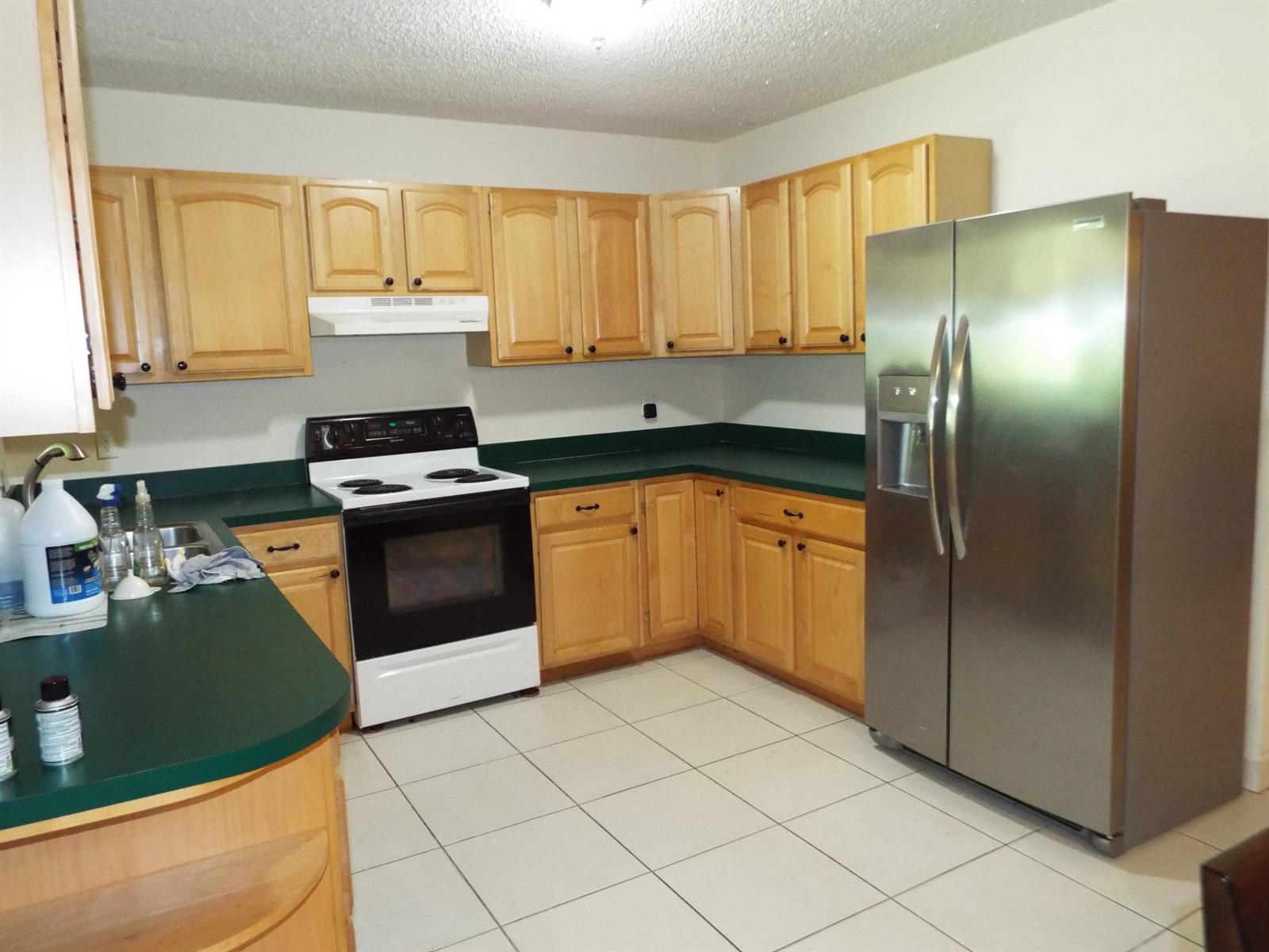 A kitchen with light wood cabinets, green countertops, white appliances, and white tile flooring — 490 SE 3rd Avenue, Pompano Beach FL 33060, POMPANO BEACH, FL