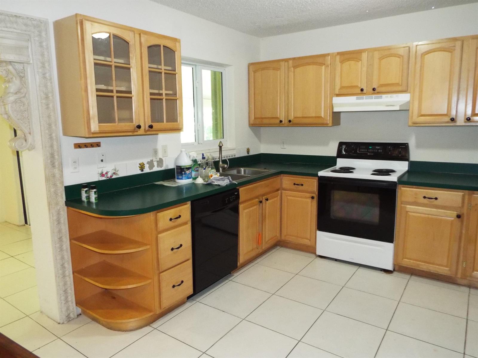 A kitchen with light wood cabinets, green countertops, a white stove, and white tile flooring — 490 SE 3rd Avenue, Pompano Beach FL 33060, POMPANO BEACH, FL