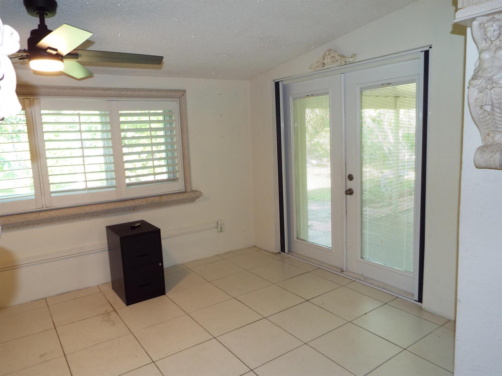 A room with white tile floors, a ceiling fan, a window with shutters, and glass doors — 490 SE 3rd Avenue, Pompano Beach FL 33060, POMPANO BEACH, FL