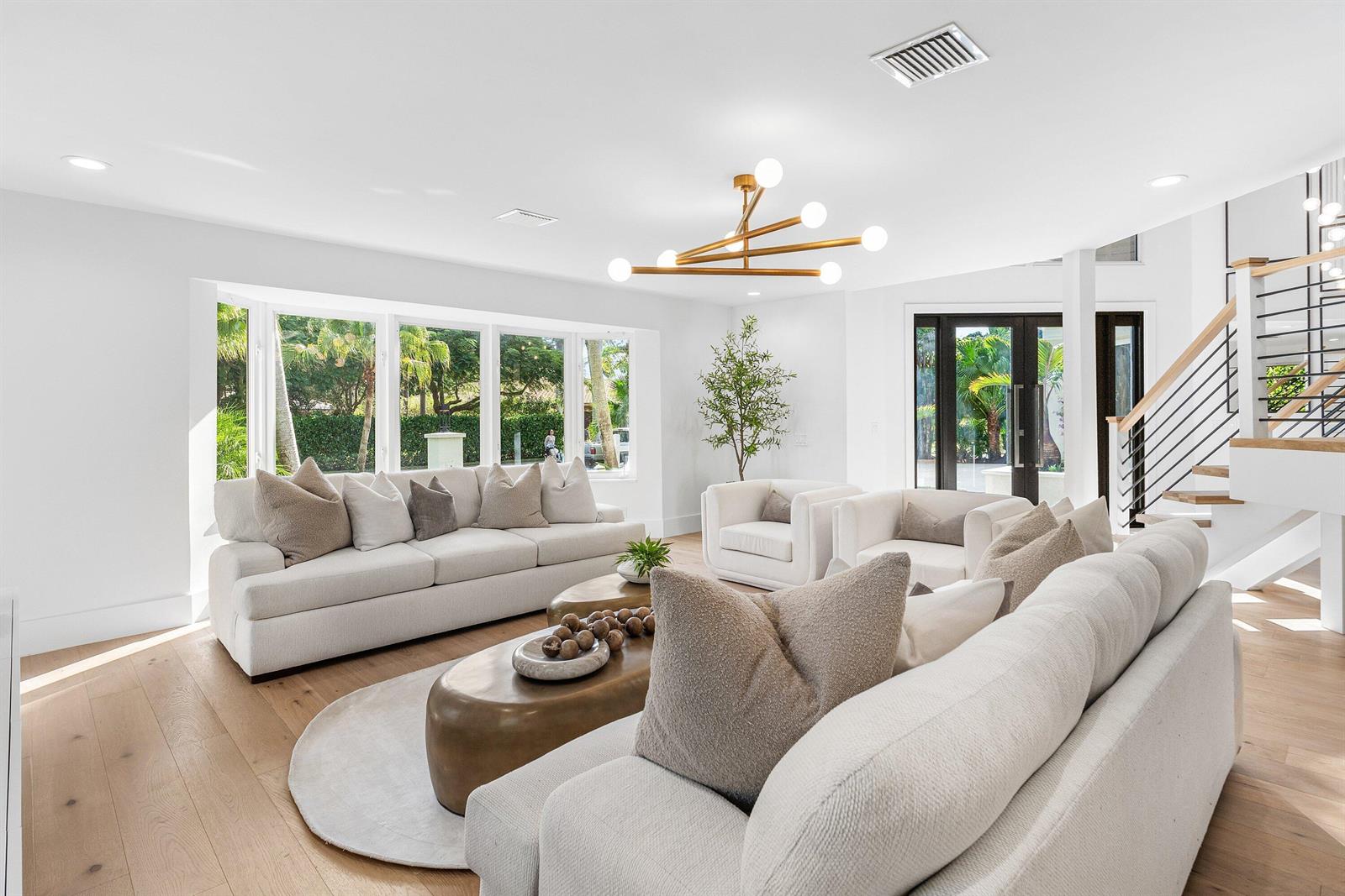 A bright living room features white sofas, gold coffee tables, and a modern light fixture — 2570 Avenue Au Soleil, Delray Beach FL 33483, DELRAY BEACH, FL
