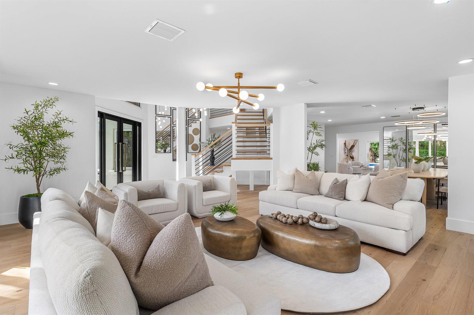 A bright, open-concept living room features white sofas, two brass coffee tables, and a staircase — 2570 Avenue Au Soleil, Delray Beach FL 33483, DELRAY BEACH, FL