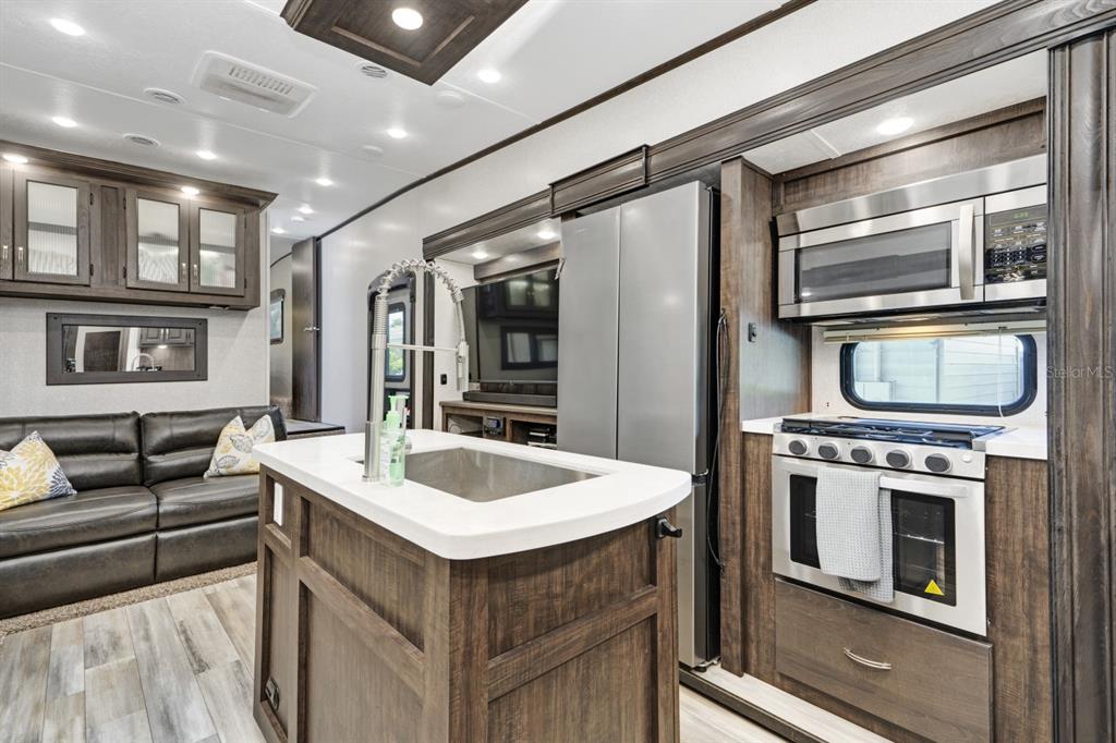 A kitchen island with a sink sits in front of a refrigerator, stove, and sofa — 305 LINDEN DRIVE UNIT Fifth wheel, ELLENTON, FL