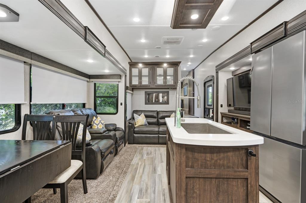 The interior of a recreational vehicle features a kitchen island, living area, and dining table — 305 LINDEN DRIVE UNIT Fifth wheel, ELLENTON, FL