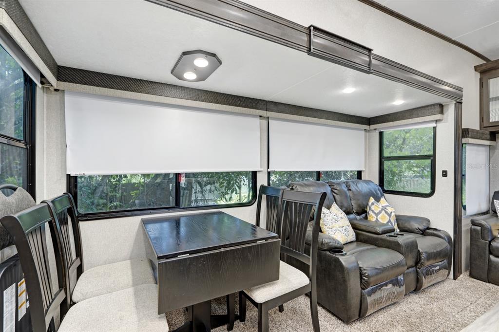 An RV interior featuring a dining table with chairs and dark leather reclining theater seats — 305 LINDEN DRIVE UNIT Fifth wheel, ELLENTON, FL