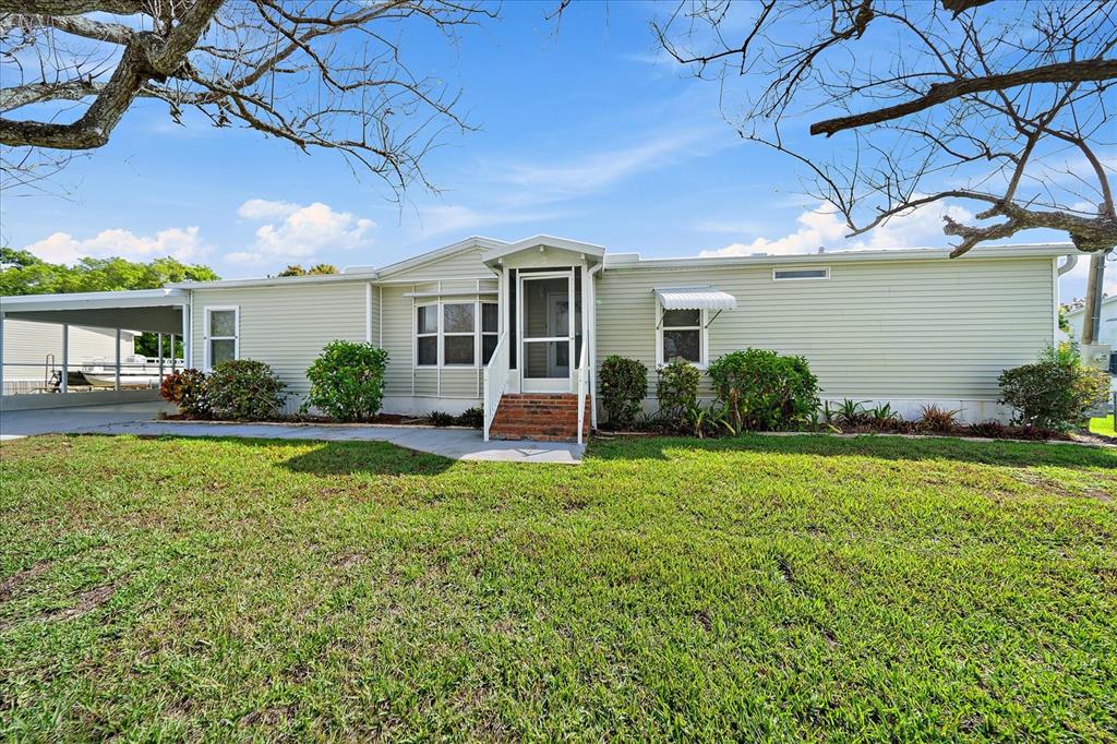 A single-story mobile home with light green siding, a carport, and a front porch — 3028 BAMBOO COURT, PUNTA GORDA, FL
