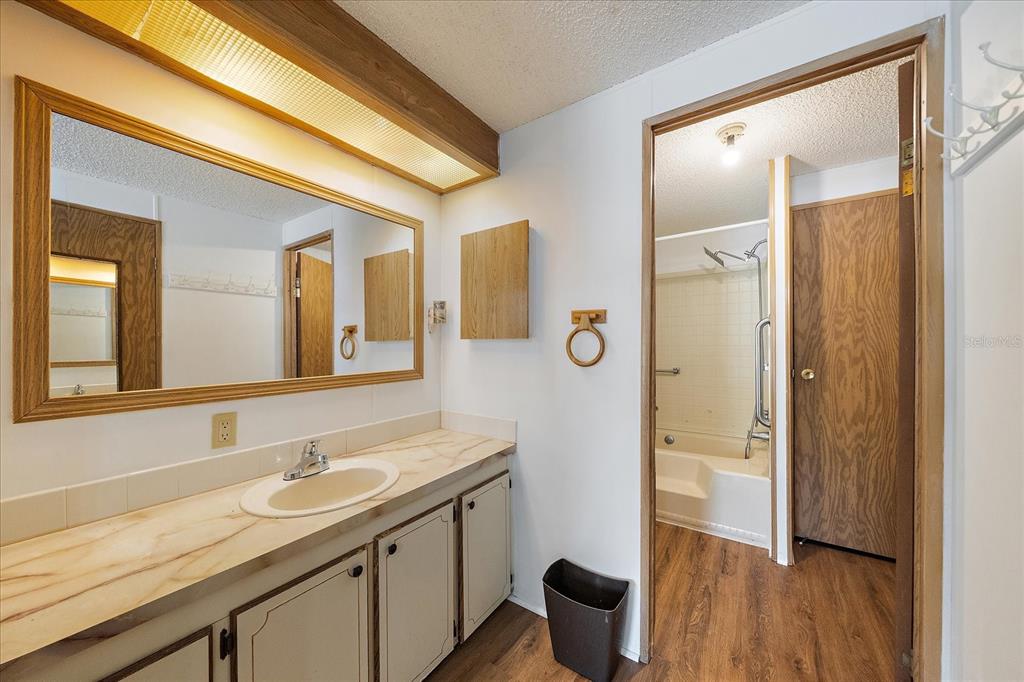 A bathroom features a vanity with a marble-look countertop, a large mirror, and wood cabinetry — 3028 BAMBOO COURT, PUNTA GORDA, FL