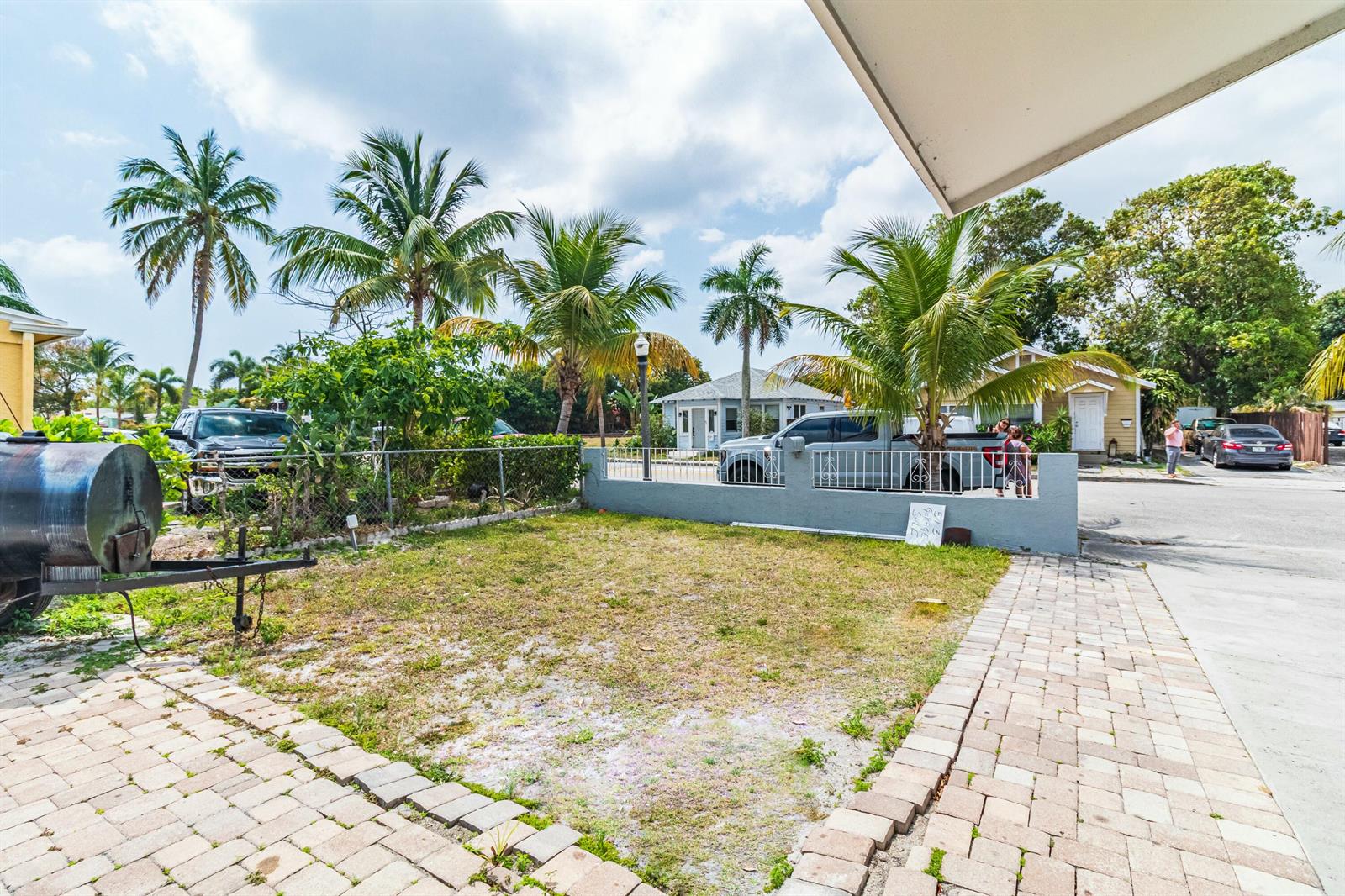 A residential yard features a paved driveway, a small lawn, and a metal fence — 513 El Vedado, West Palm Beach FL 33405, WEST PALM BEACH, FL