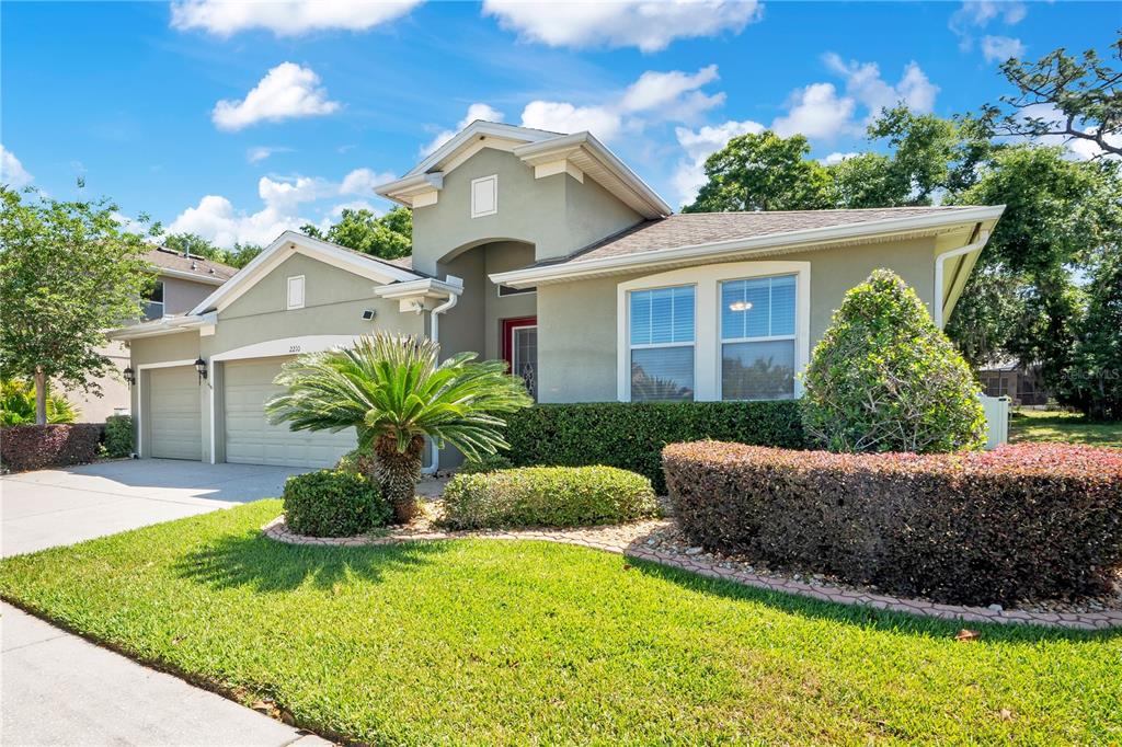A single-story suburban house with a two-car garage, stucco exterior, and manicured front landscaping — 2210 VALTERRA VISTA WAY, VALRICO, FL
