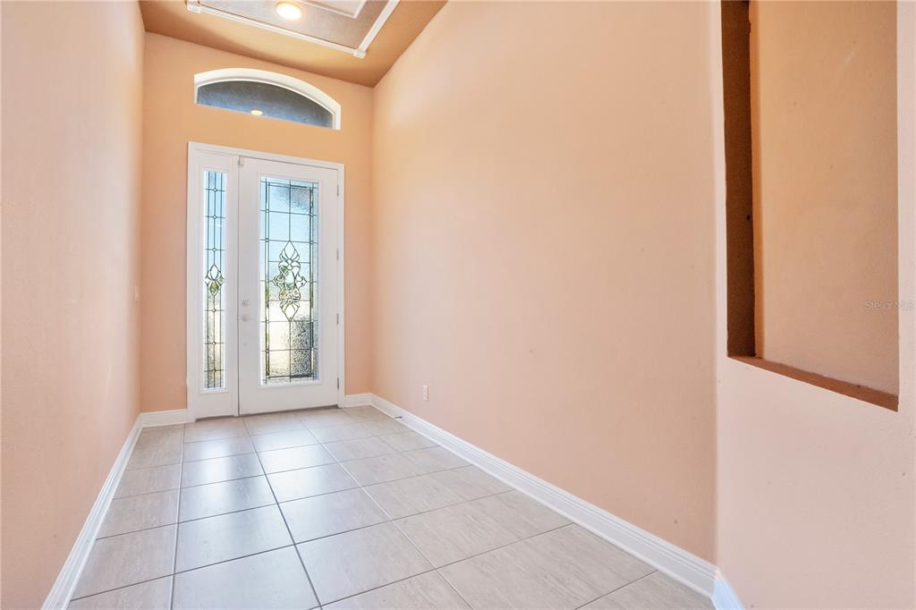 An entryway features light-colored tile flooring, peach-colored walls, and a glass-paneled front door — 2210 VALTERRA VISTA WAY, VALRICO, FL