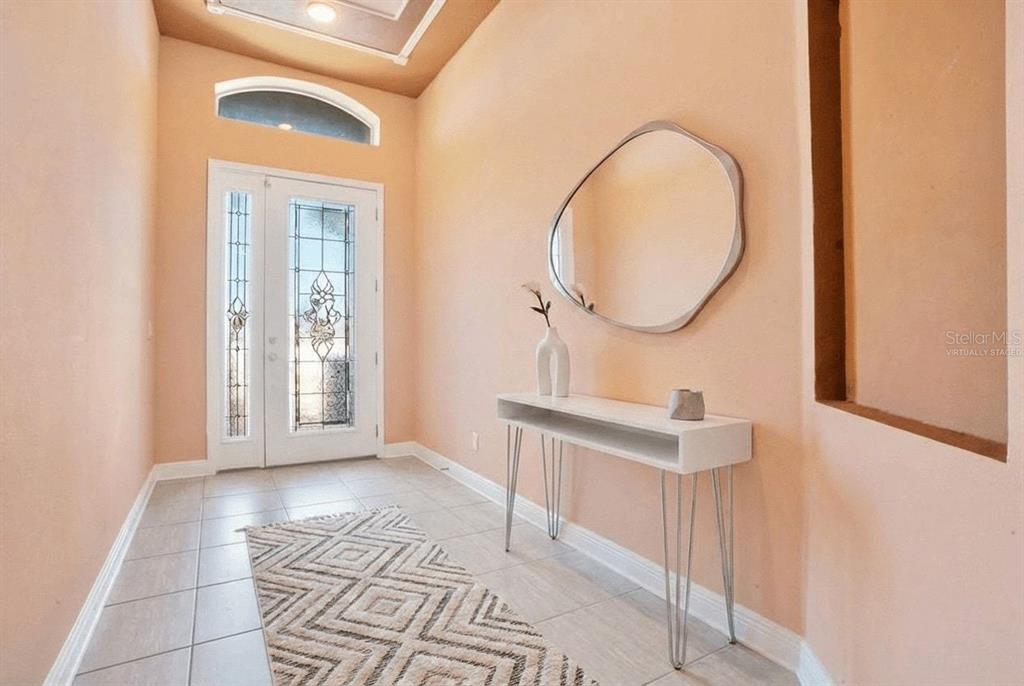 An entryway features a white console table, a mirror, a patterned rug, and a glass-paneled door — 2210 VALTERRA VISTA WAY, VALRICO, FL