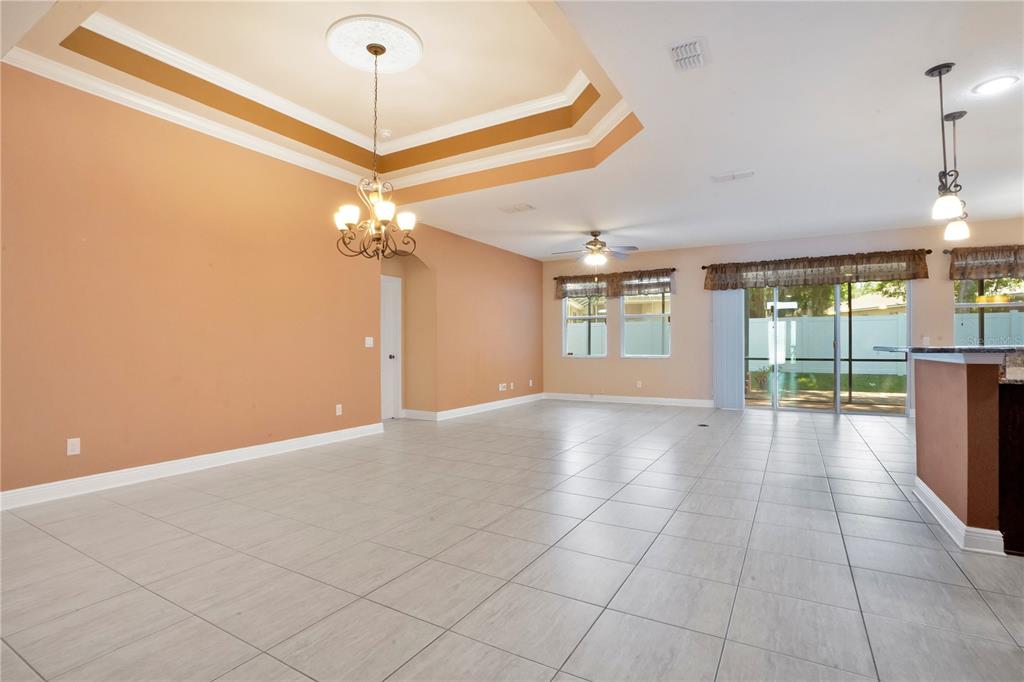 A spacious living area features light tile flooring, a tray ceiling, and a chandelier — 2210 VALTERRA VISTA WAY, VALRICO, FL