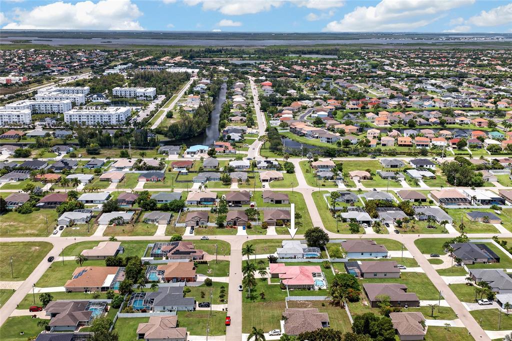 An aerial view shows a residential neighborhood with a white arrow pointing to a house — 1821 SW 22ND TERRACE, CAPE CORAL, FL