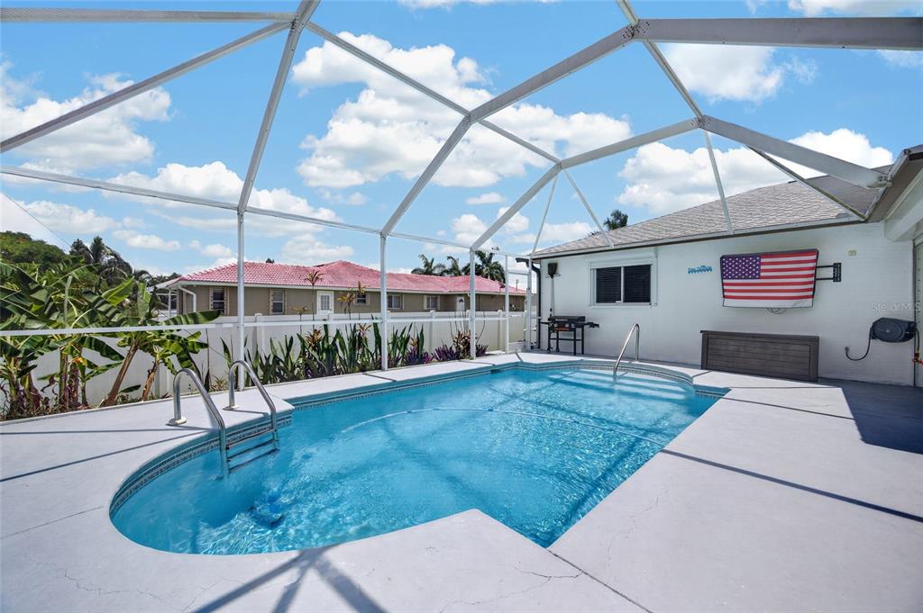 A screened-in swimming pool with a concrete deck and an American flag on the wall — 1821 SW 22ND TERRACE, CAPE CORAL, FL