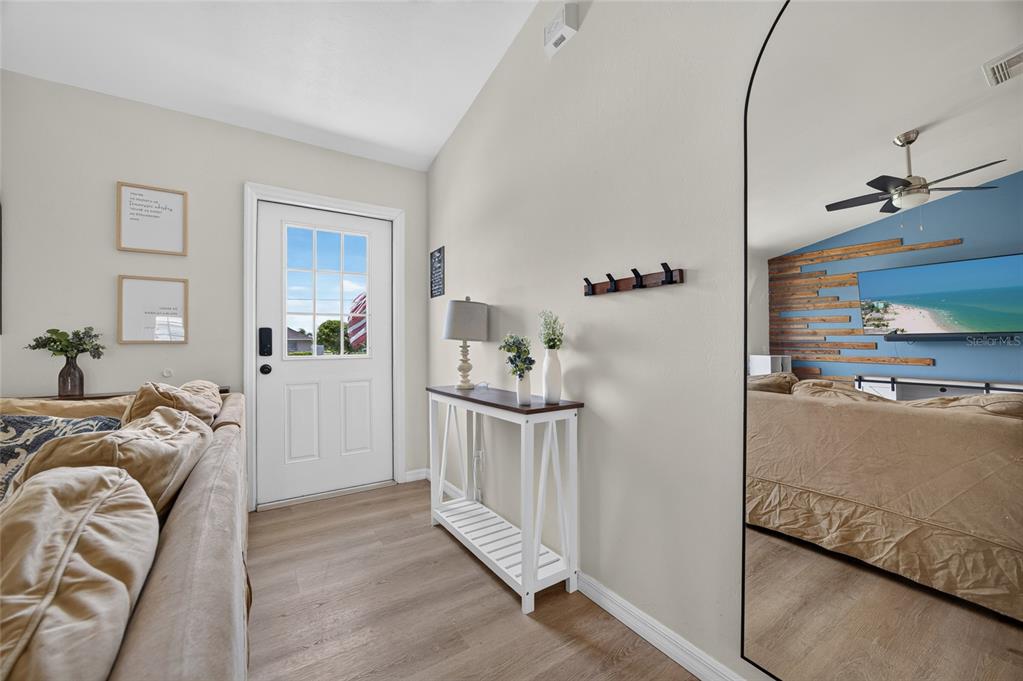 A living room entryway features a white door, a console table, and a large wall mirror — 1821 SW 22ND TERRACE, CAPE CORAL, FL