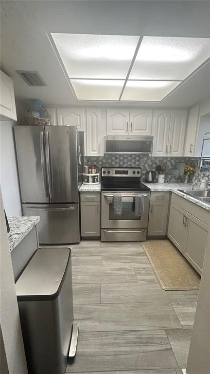 A kitchen features stainless steel appliances, white upper cabinets, light gray lower cabinets, and tile flooring — 5059 LIVE OAK CIRCLE UNIT 5059, BRADENTON, FL