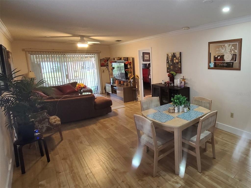 A living and dining area features light wood flooring, a ceiling fan, and sliding glass doors — 5059 LIVE OAK CIRCLE UNIT 5059, BRADENTON, FL