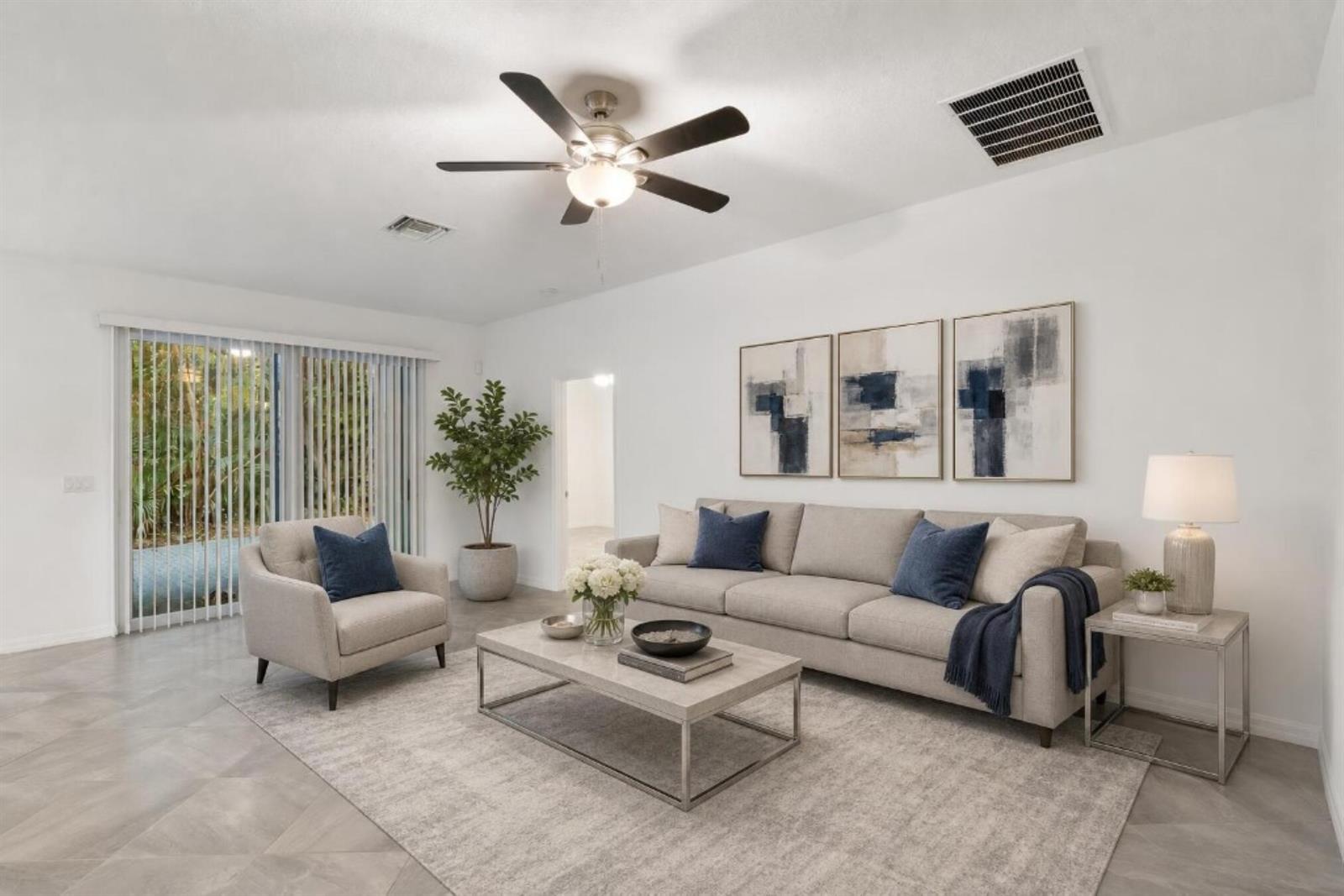 A living room features a beige sofa, armchair, coffee table, and abstract wall art — 2055 46th Avenue, Vero Beach FL 32966, VERO BEACH, FL