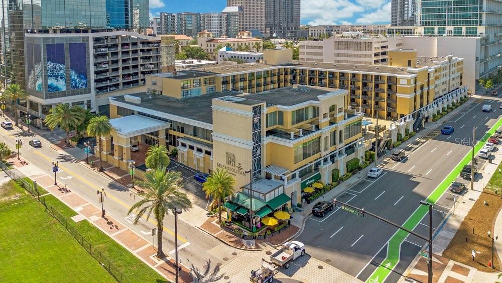 An aerial view of a yellow multi-story building with a restaurant and street-level parking — 151 E WASHINGTON STREET UNIT 217, ORLANDO, FL