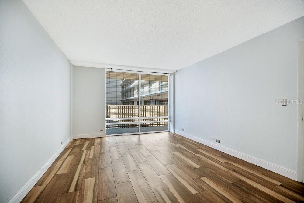 An empty room with light blue walls, wood-look tile flooring, and a large sliding glass door — 151 E WASHINGTON STREET UNIT 217, ORLANDO, FL