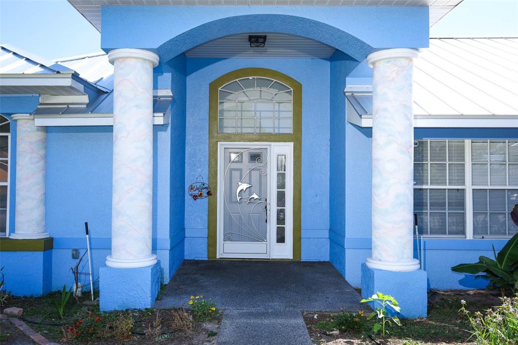 The exterior of a blue house features a front entrance with two decorative columns — 1932 MONTEREY DRIVE, DELTONA, FL