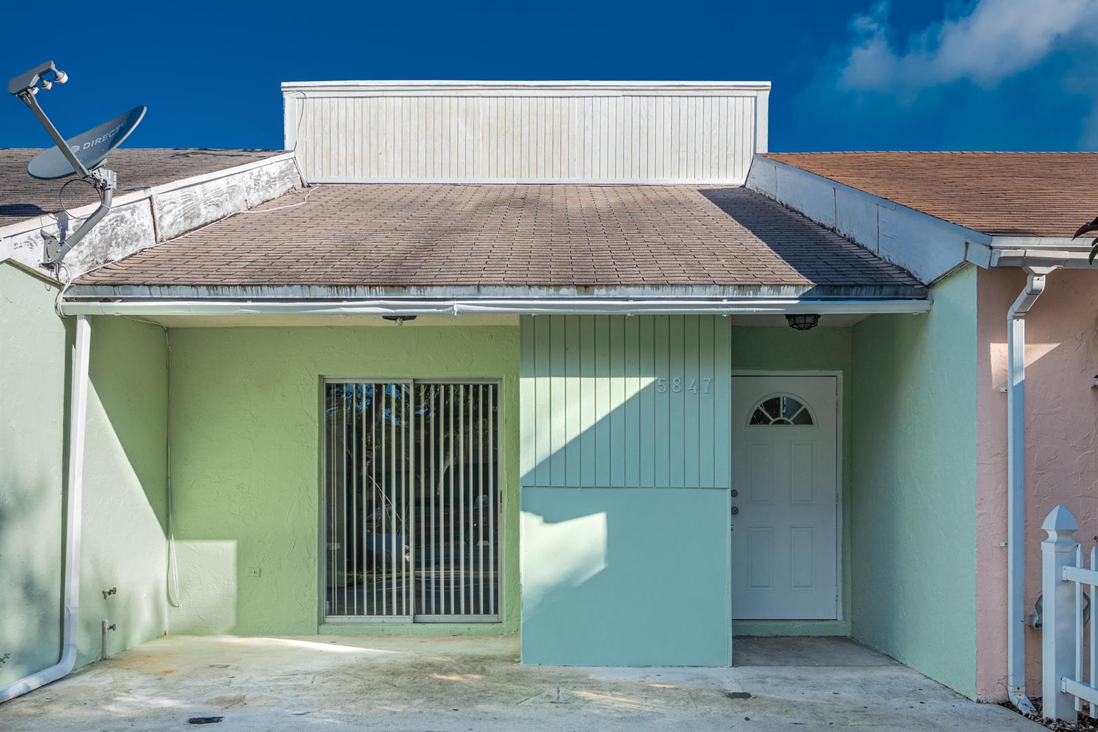 The exterior of a light green home features a sliding glass door and a white door — 5847 S 37th Street, FL 33463, FL