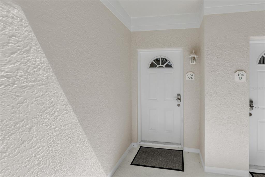 A white front door with a semi-circular window sits next to another unit entrance — 3401 54TH DRIVE W UNIT 104, BRADENTON, FL