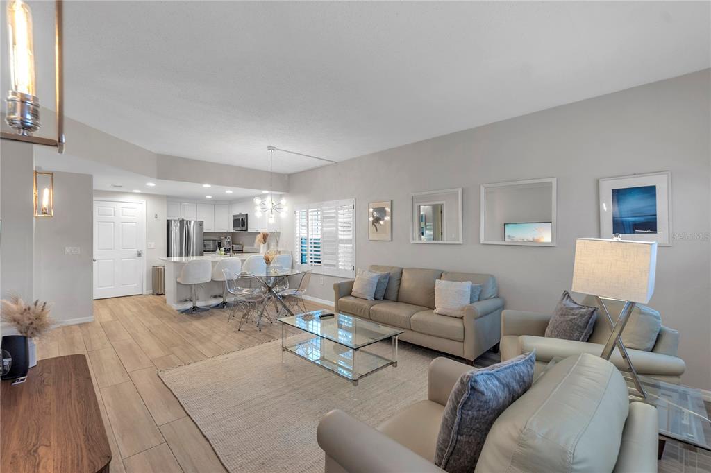 A living room with light-colored tile floors, a beige sofa, and an open-concept kitchen — 3401 54TH DRIVE W UNIT 104, BRADENTON, FL