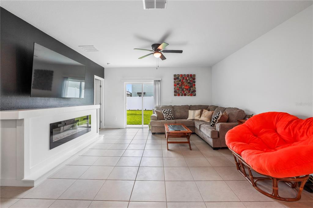 A living room features a fireplace, a large television, a sectional sofa, and a red chair — 629 BALD CYPRESS DRIVE, LAKELAND, FL