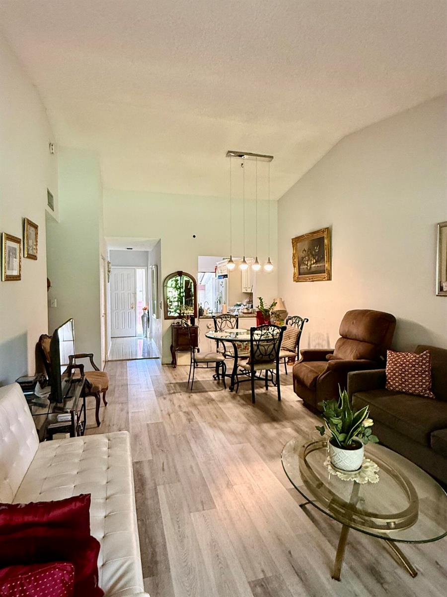 A living and dining area with wood-look flooring, a glass coffee table, and pendant lighting — 3927 Vine Tree Trail # B, Lake Worth FL 33467, LAKE WORTH, FL