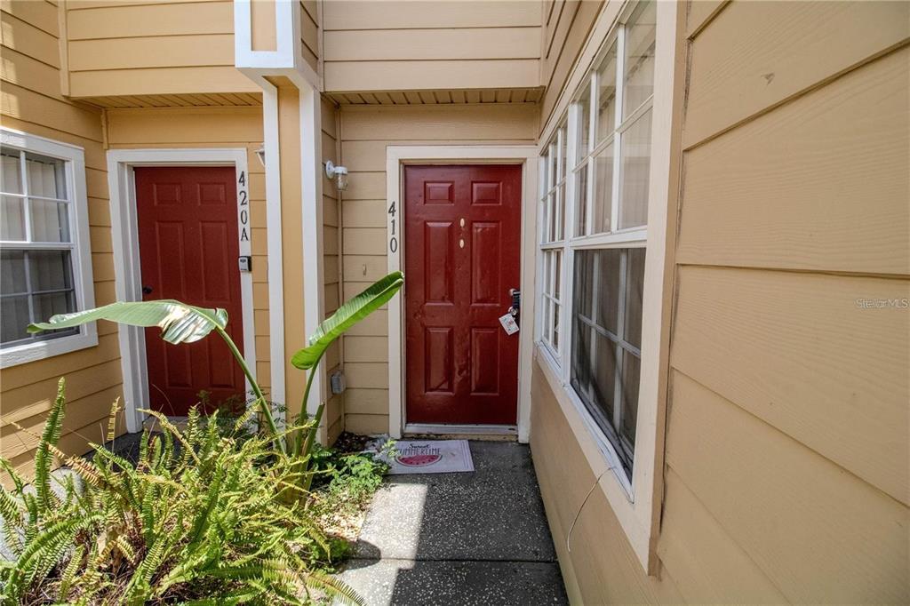 An exterior view shows two red front doors with house numbers on a tan building — 410 AUSTRALIAN WAY, DAVENPORT, FL