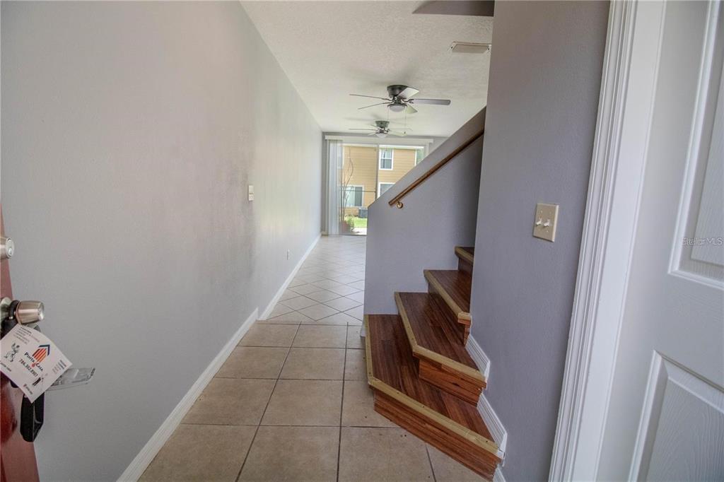 An entryway with tile flooring leads to a staircase with wood treads and a living area — 410 AUSTRALIAN WAY, DAVENPORT, FL