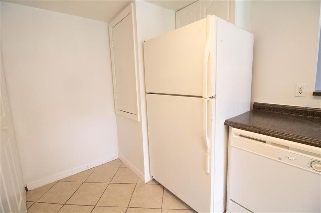 A white refrigerator stands in a kitchen corner next to a dishwasher and tiled floor — 410 AUSTRALIAN WAY, DAVENPORT, FL