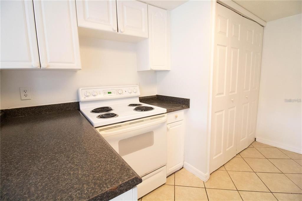 A kitchen features white cabinets, a white electric stove, and dark countertops over tiled floors — 410 AUSTRALIAN WAY, DAVENPORT, FL
