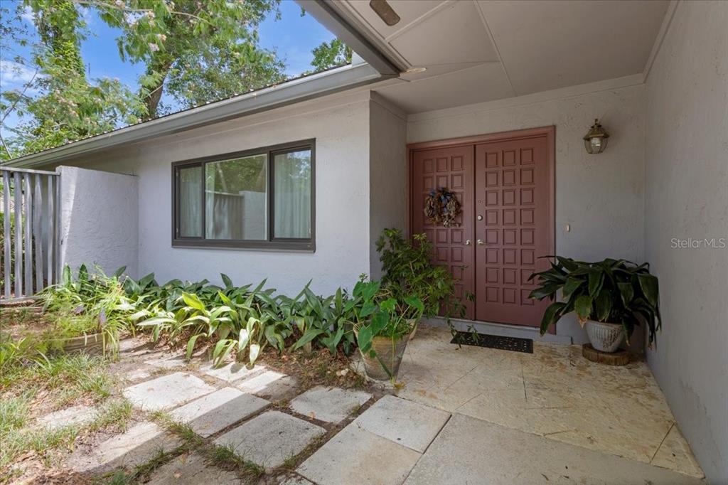 A light-colored house exterior features a double front door, a large window, and landscaping — 4003 NW 34TH PLACE, GAINESVILLE, FL