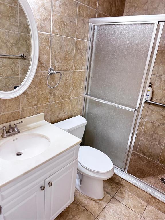 A bathroom features a white vanity, a toilet, and a glass-enclosed shower with tiled walls — 11088 NW 23RD COURT, SUNRISE, FL