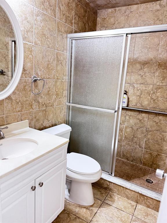 A bathroom features a white vanity, a toilet, and a glass-enclosed shower with brown tiles — 11088 NW 23RD COURT, SUNRISE, FL