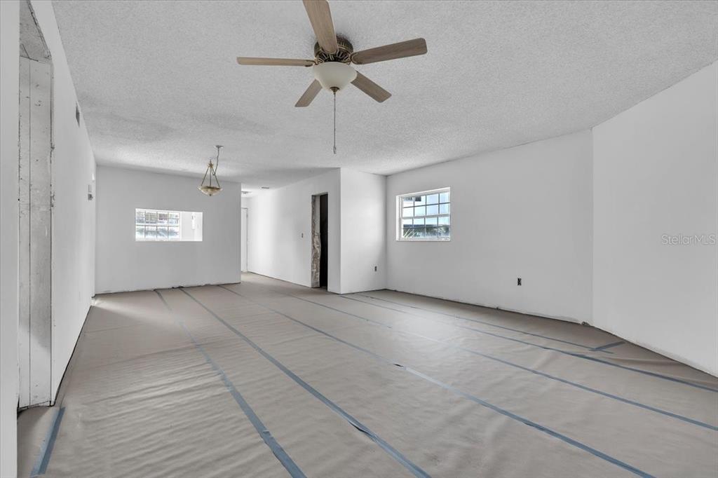 An empty room with white walls, a ceiling fan, and protective paper covering the floor — 7043 NEW POST DRIVE UNIT 1, NORTH FORT MYERS, FL