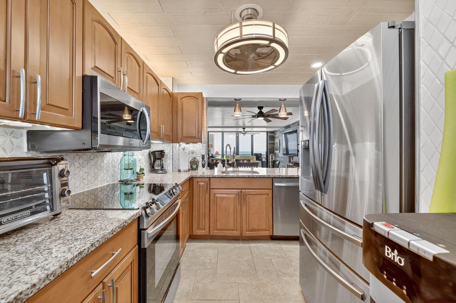 A kitchen with wood cabinets, stainless steel appliances, granite countertops, and a view of the ocean — 10680 S Ocean Drive # 105, Jensen Beach FL 34957, JENSEN BEACH, FL