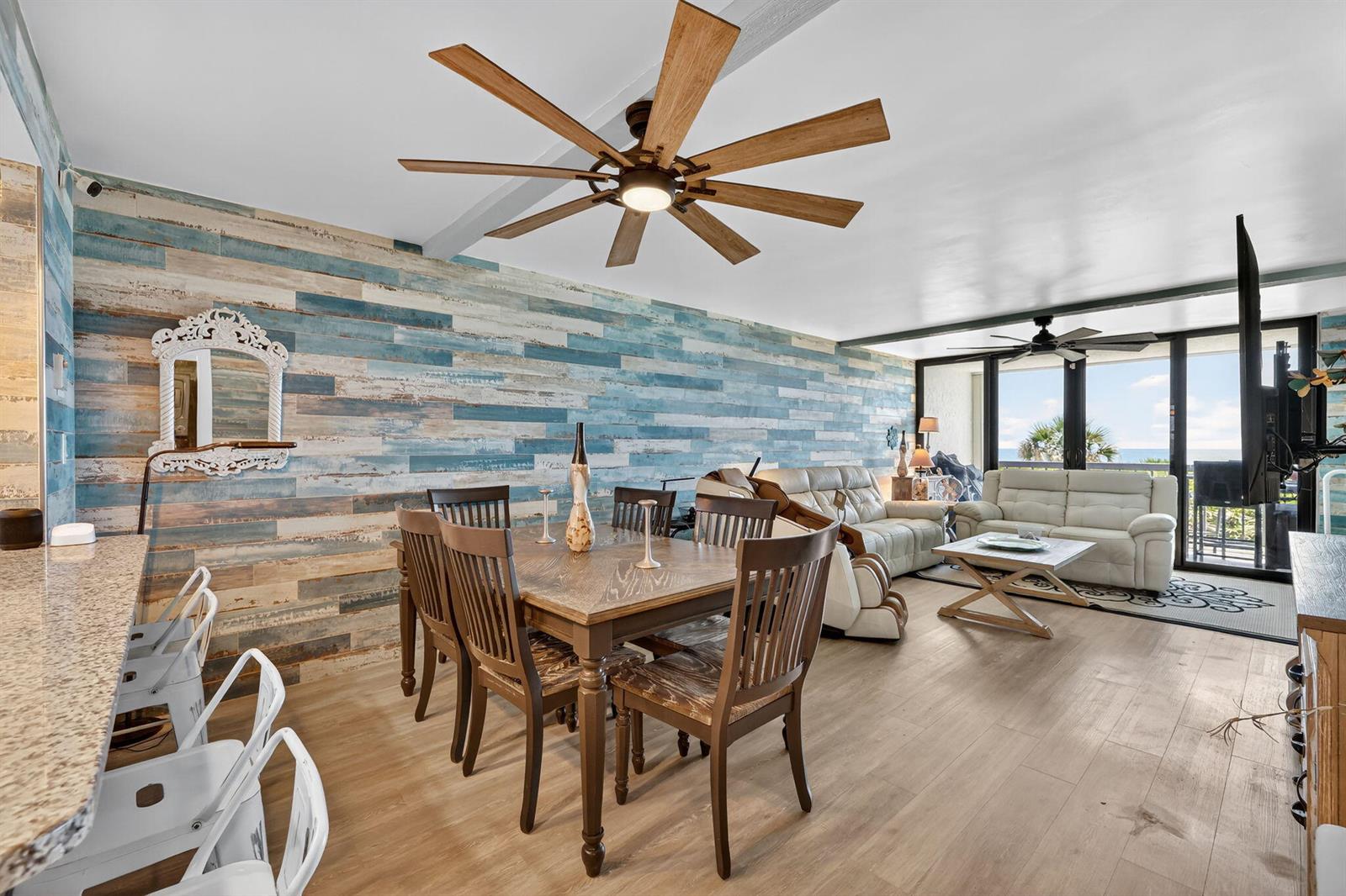 A dining and living area features a blue wood-plank accent wall and ceiling fans — 10680 S Ocean Drive # 105, Jensen Beach FL 34957, JENSEN BEACH, FL