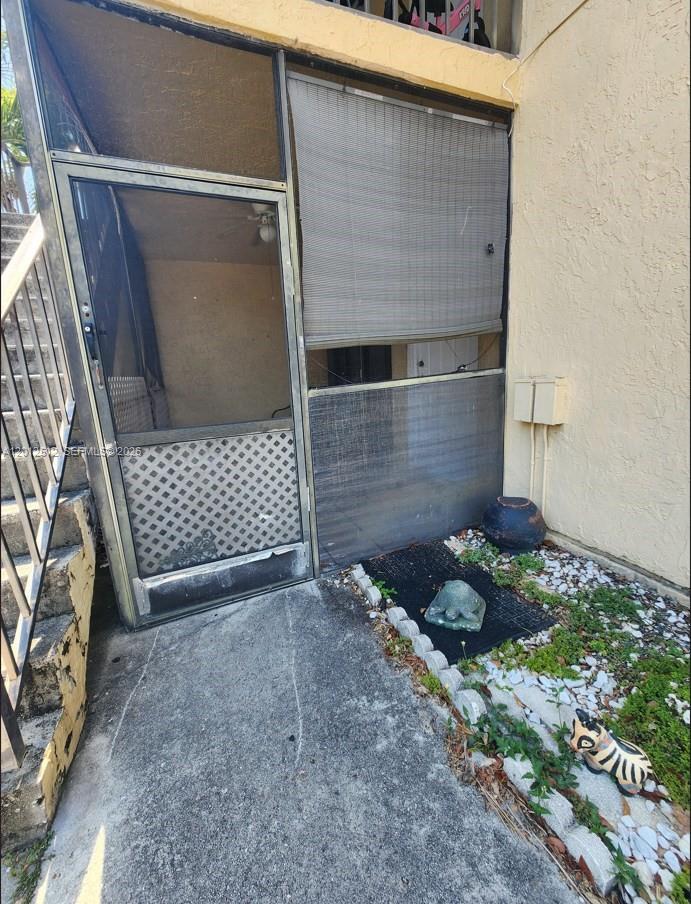 A screened-in patio entrance features a metal door, a bamboo shade, and garden decorations — 15619 SW 73rd Cir Ter # 9, Miami FL 33193, MIAMI, FL